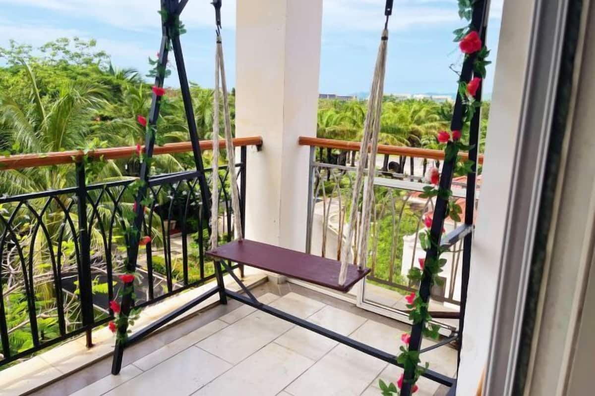 Un balcon avec un banc en bois, des rampes en métal et une vue sur la verdure et les bâtiments.