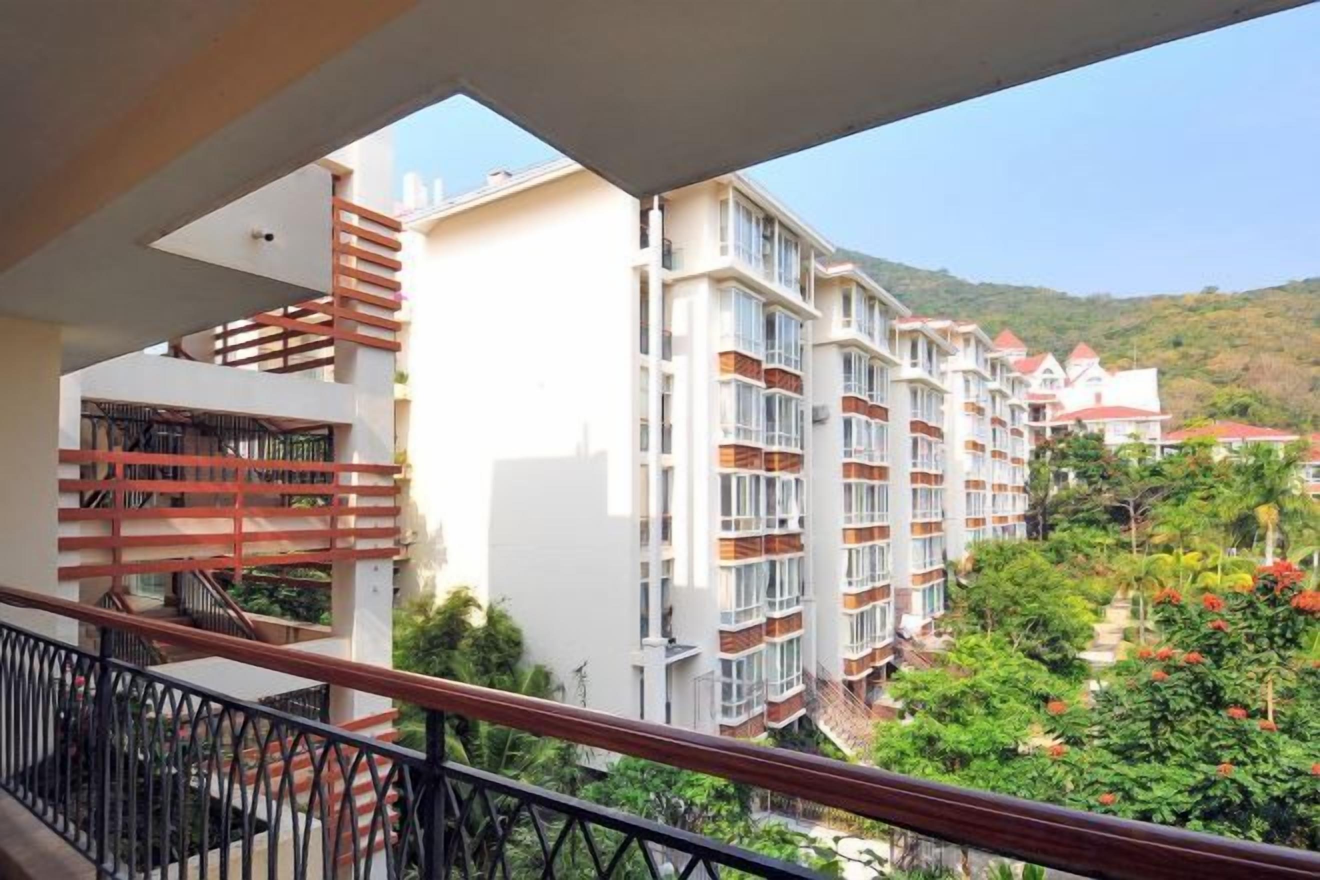 Ein mehrstöckiges Hotel mit Balkonen, Blick auf eine Hügelkette und einem klaren Himmel.