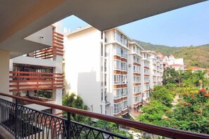 Egy többemeletes szálloda, amelynek erkélyei vannak, és ahonnan egy domboldalra és a tiszta égre nyílik kilátás.