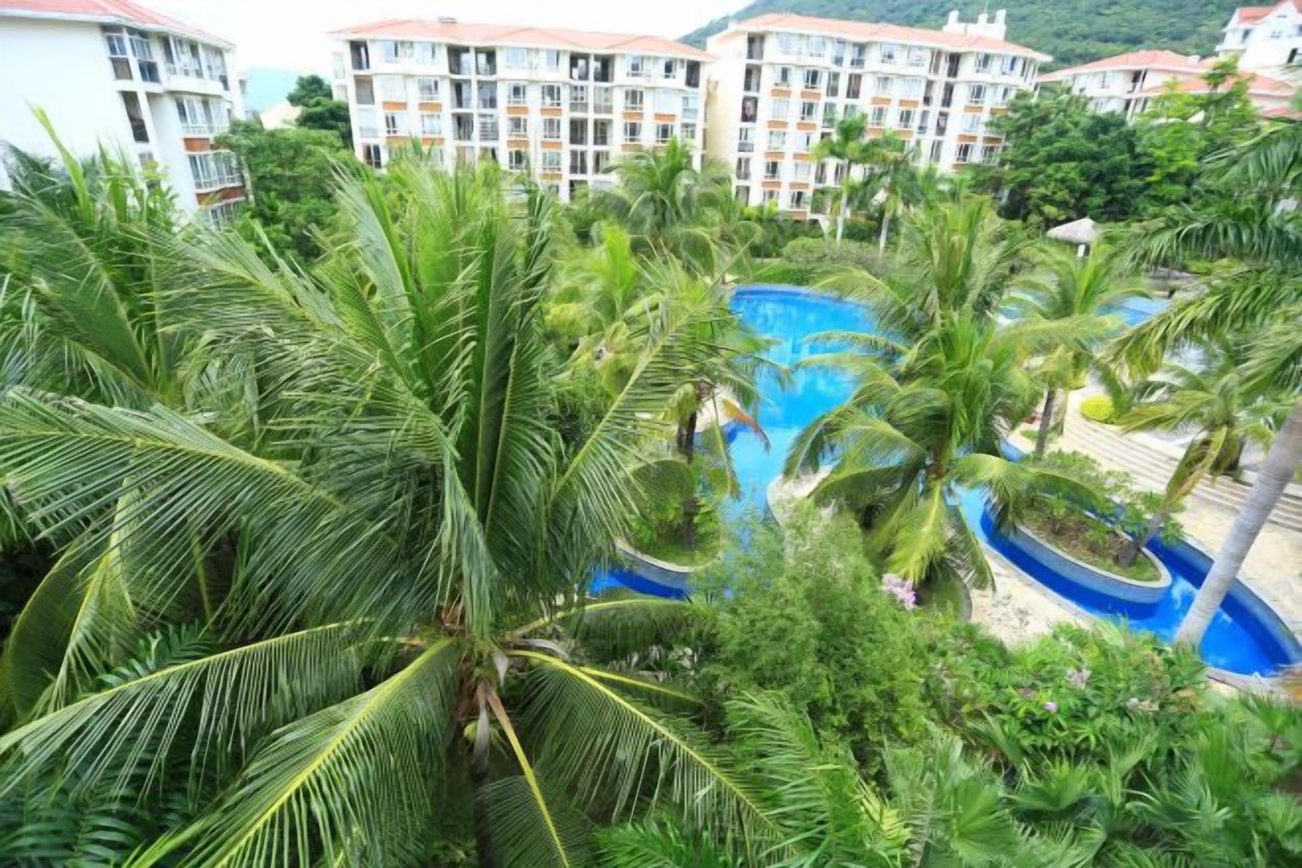 Un resort con piscina circondata da palme e palazzi a più piani.