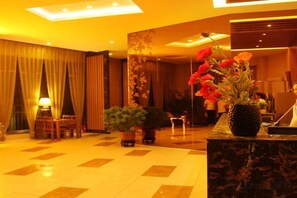 A hotel lobby with a reception desk, seating area, and a large potted plant with red flowers. - Beijing Sky House Business Hotel (Capital Airport Xinguozhan Branch) (Beijing)