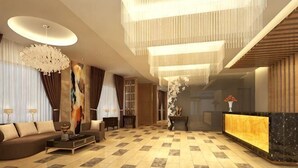 A spacious lobby with a reception desk, a sofa, and a chandelier.