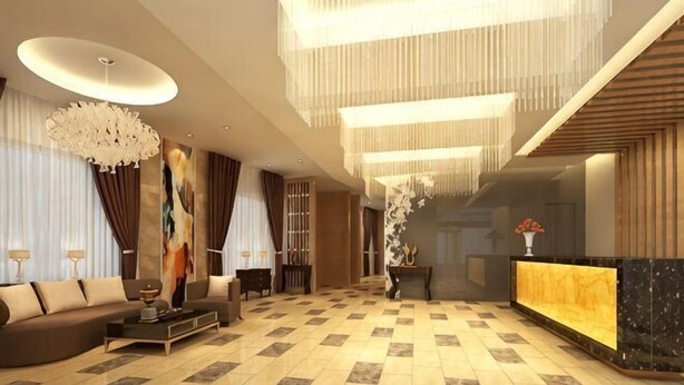 A spacious lobby with a reception desk, a sofa, and a chandelier.