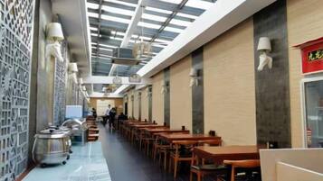 A corridor with tables and chairs, a ceiling with skylights, and a wall with a decorative pattern.