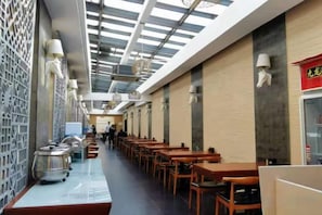 A corridor with tables and chairs, a ceiling with skylights, and a wall with a decorative pattern. - Beijing Sky House Business Hotel (Capital Airport Xinguozhan Branch) (Beijing)