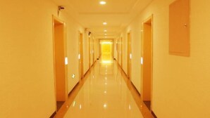 A long, narrow hotel corridor with doors on both sides and a bright, reflective floor.