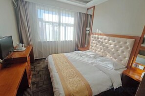 Una habitación de hotel con una cama grande, un televisor sobre un escritorio de madera y una ventana con cortinas.