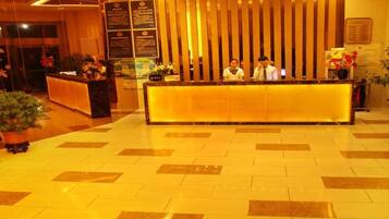A hotel reception area with a reception desk, a vertical wooden panel, and a tiled floor.
