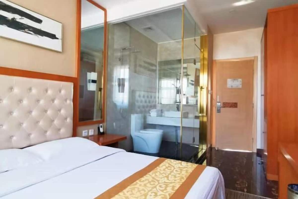 Hotelkamer met een bed, een douchecabine, een badkamer met spiegel en een deur.