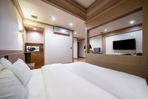 Habitació d'hotel amb llit, televisió, microones i petita cuineta.