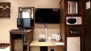 A room with a wooden desk, a television mounted on the wall, a microwave, and a refrigerator. - Hotel Cullinan Yongin (Yongin-si)