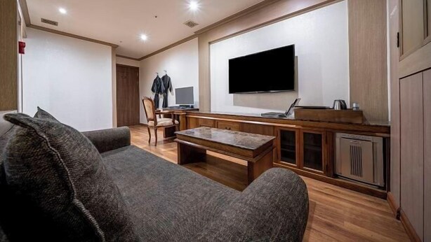 Una sala de estar con un sofá, una mesa de centro, televisor y una mesita con una computadora portátil.