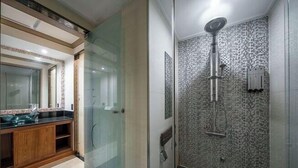 A bathroom with a glass shower enclosure, a wooden vanity, and a tiled backsplash. - Hotel Cullinan Yongin (Yongin-si)