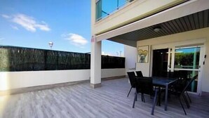 An outdoor patio area with a table and chairs, a view of the sky, and a building in the background. - Almogrote Sunset South (San Miguel de Abona)