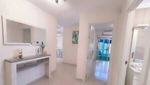A hallway with a white console table, a mirror, and a door leading to another room. - Almogrote Sunset South (San Miguel de Abona)