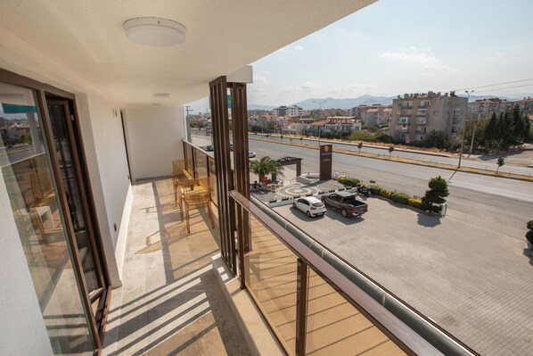 Un balcon donnant sur une rue de la ville, une aire de stationnement et une enseigne d’hôtel.