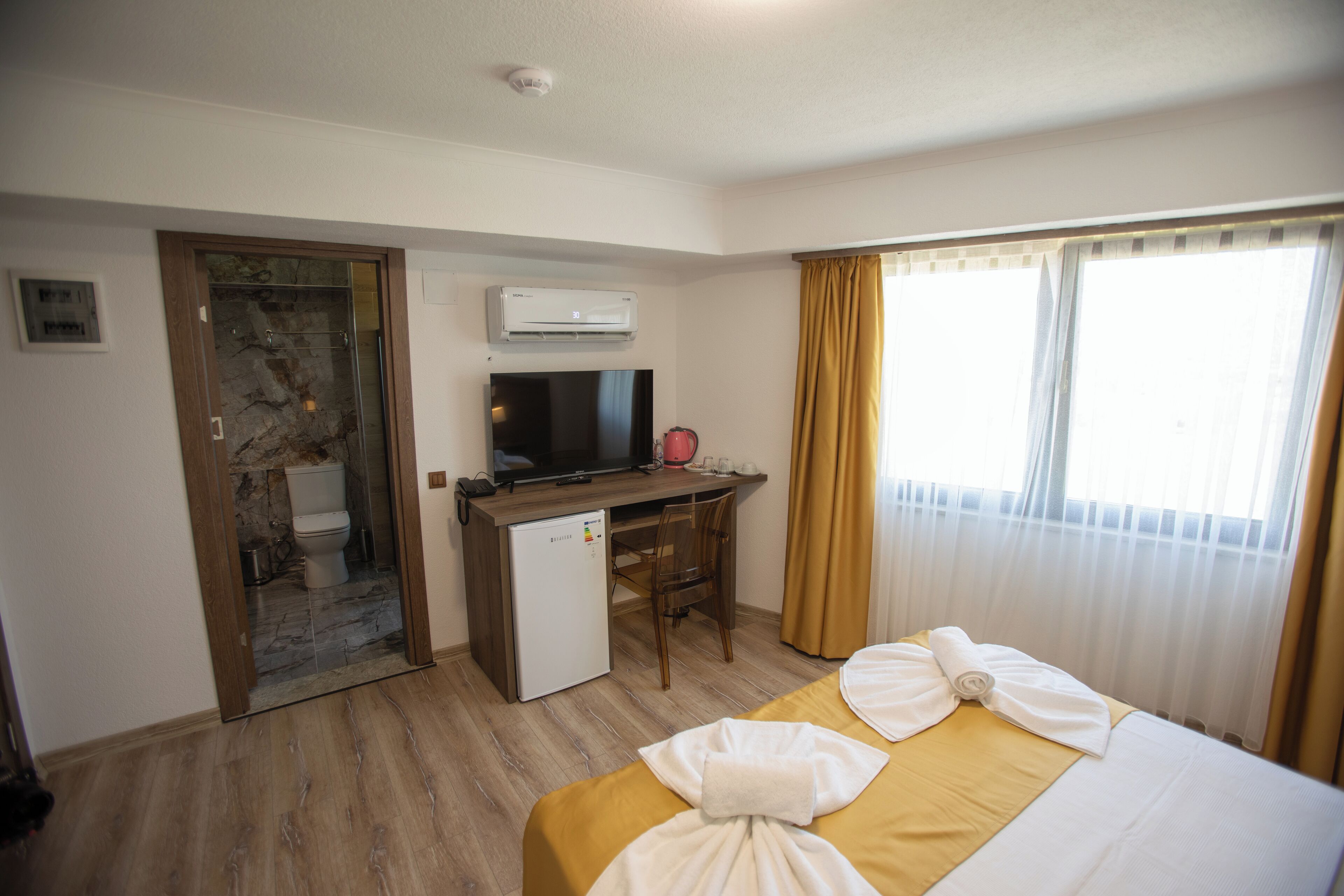 A hotel room with a bed, a desk, a television, and a small refrigerator.