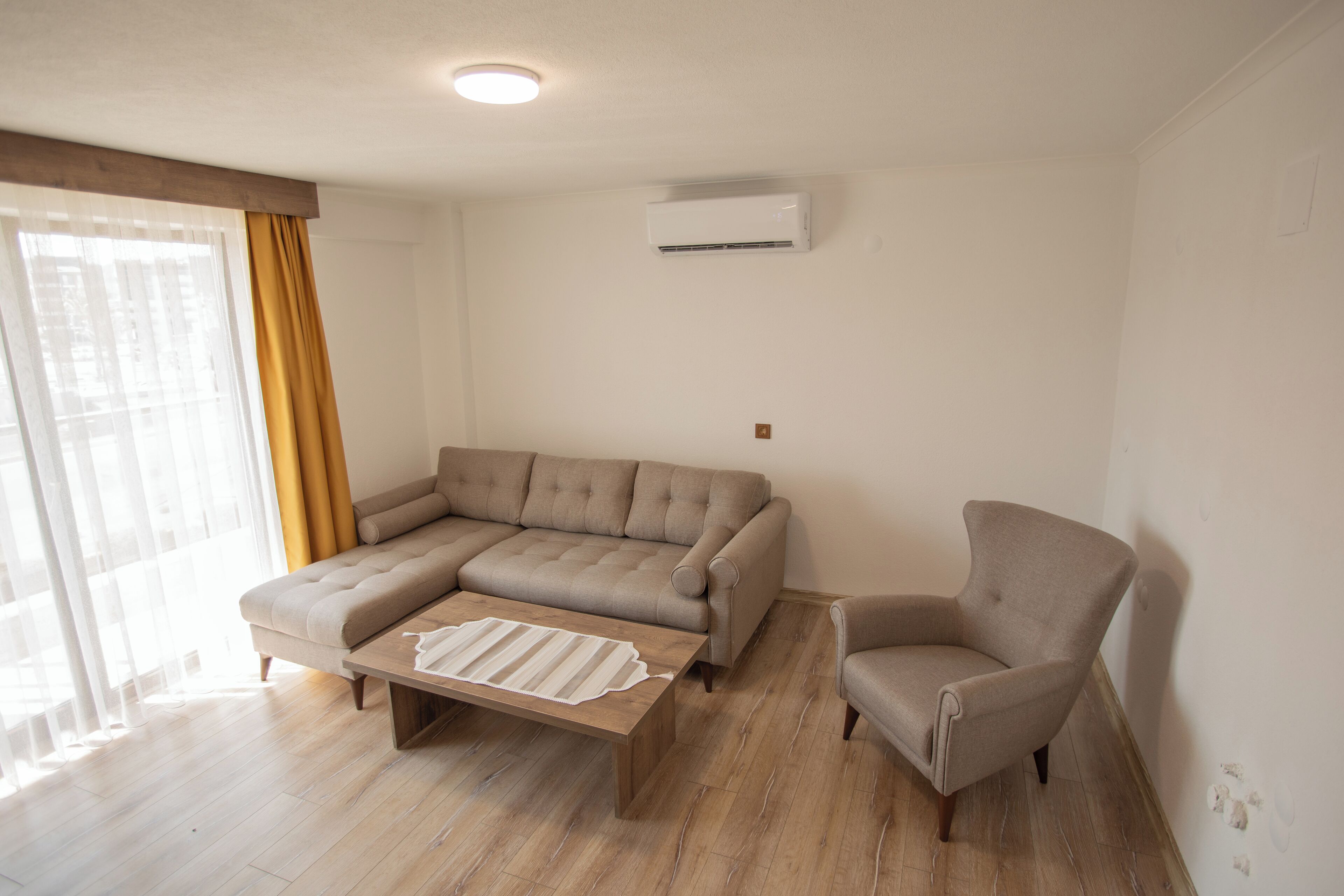 Una sala de estar con un sofá seccional, un sillón individual y una mesa de centro de madera.