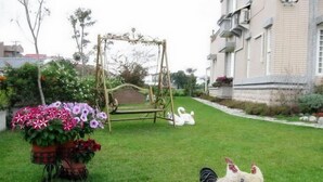 A garden with a swing set, a swan decoration, and chickens. - Evergreen Garden House (Hualien)