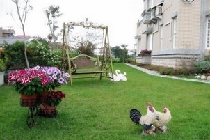 Um jardim com baloiço, uma decoração de cisne e galinhas.