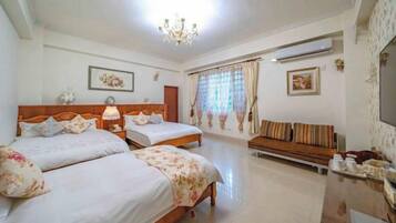 Una habitación de hotel con dos camas, un sofá, una araña y un espejo grande.