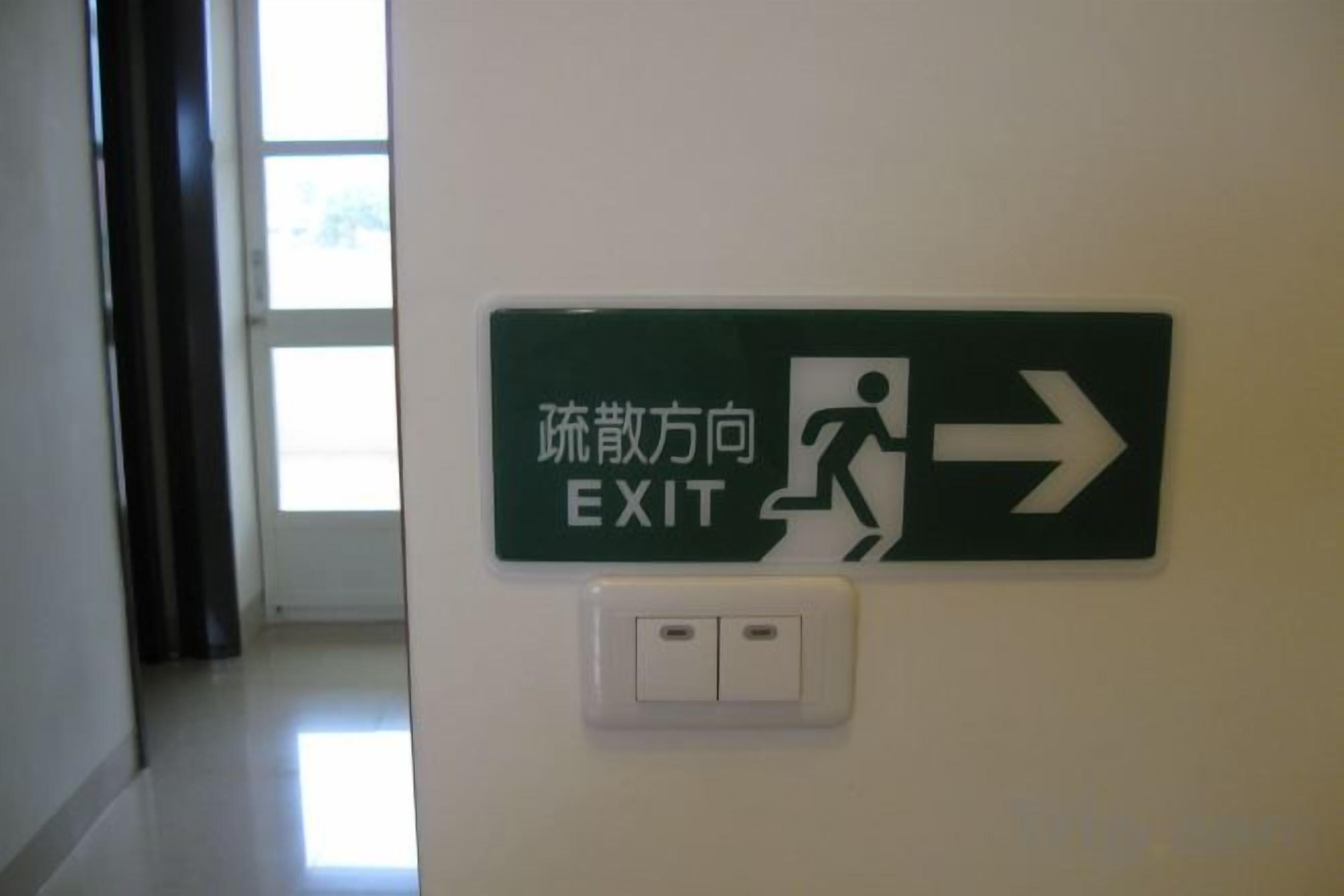 An exit sign with a directional arrow and a pictogram of a person running.