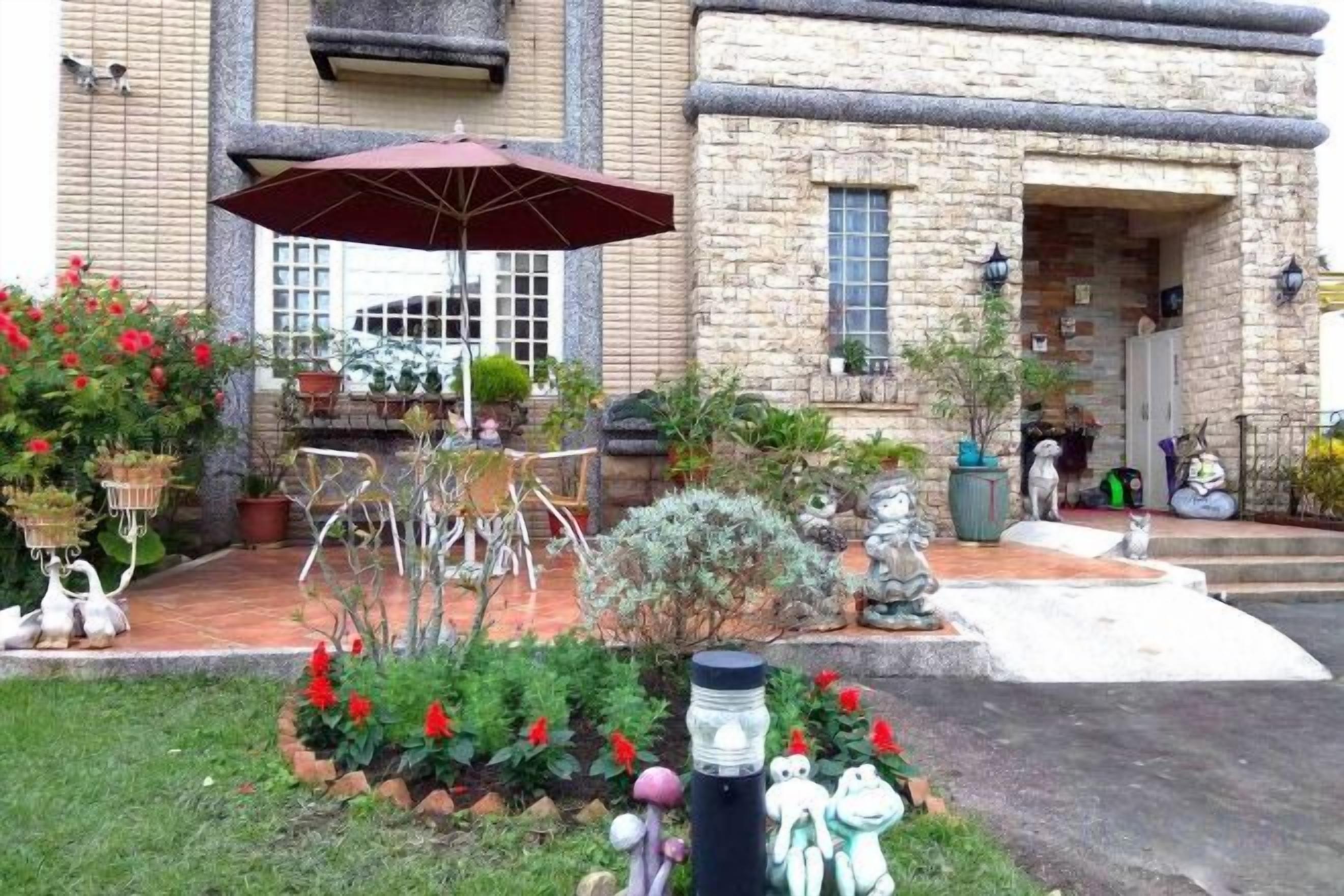 Un bâtiment en pierre doté d’un patio aménagé avec des meubles d’extérieur, des plantes en pot et des statues décoratives.