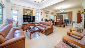A spacious living room with leather sofas, a TV, and a dining area with wooden furniture. - Evergreen Garden House (Hualien)