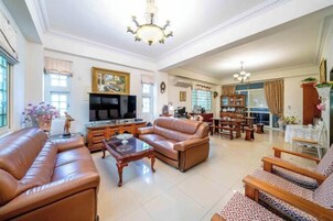 Un amplio salón con sofás de cuero, televisión y zona de comedor con mobiliario de madera.