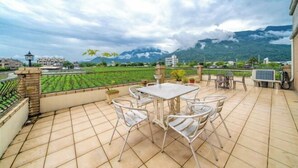 A patio with a table and chairs, a view of a green field, and mountains in the background. - Evergreen Garden House (Hualien)