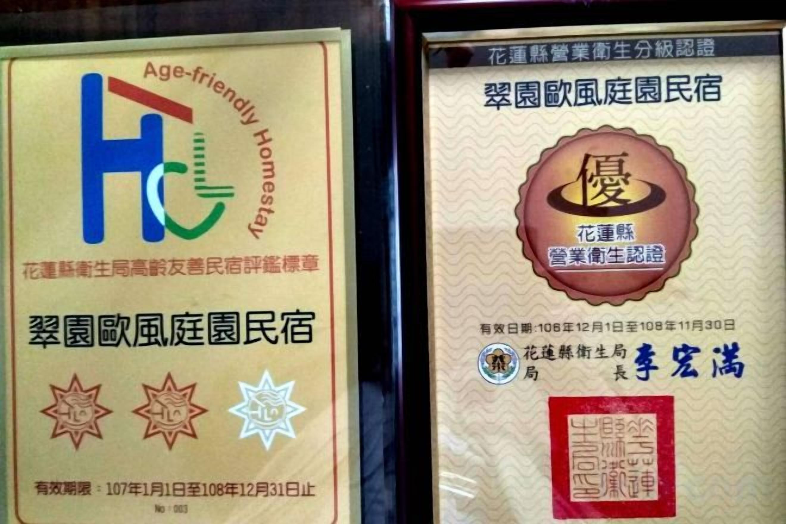 Two framed certificates, one with a blue and green logo and text, and the other with a red seal and Chinese characters.