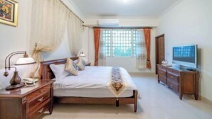 A bedroom with a bed, bedside tables, an air conditioning unit, a television, and curtains. - Evergreen Garden House (Hualien)