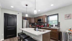 A modern kitchen with a central island, stainless steel appliances, and pendant lighting. - "Final Frontier"- Pool, Hot Tub, Pickleball, Basketball, Pond, Arcade, Putt Putt (Troutman)