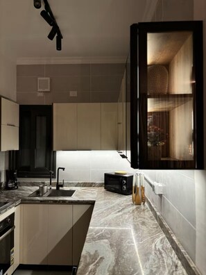 Una cucina moderna con un piano di lavoro in marmo, lavello incassato e macchina da caffè.