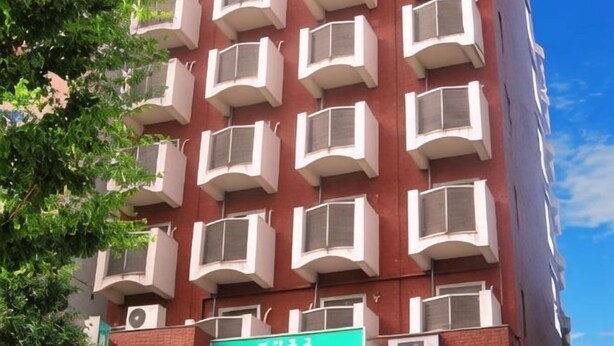 A multi-story building with a red facade and white balconies. - Shinjuku Urban Hotel (Tokyo)