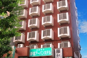 A multi-story building with a red facade and white balconies. - Shinjuku Urban Hotel (Tokyo)