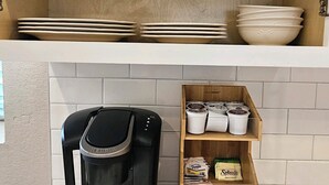 Une cuisine équipée d’une machine à café, d’étagères pour la vaisselle et d’un meuble de rangement pour les grains de café.