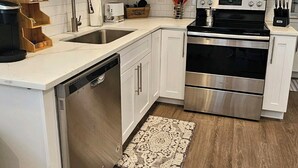 Une cuisine moderne avec des armoires blanches, des appareils en acier inoxydable et un plancher en bois.
