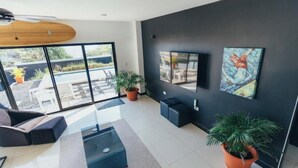 A modern living room with a glass coffee table, a sofa, and two potted plants.