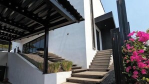 A modern house with a concrete staircase leading to a covered porch.