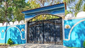 Uma entrada com portão, uma placa com a palavra 'Marbella' e detalhes em metal decorativo.