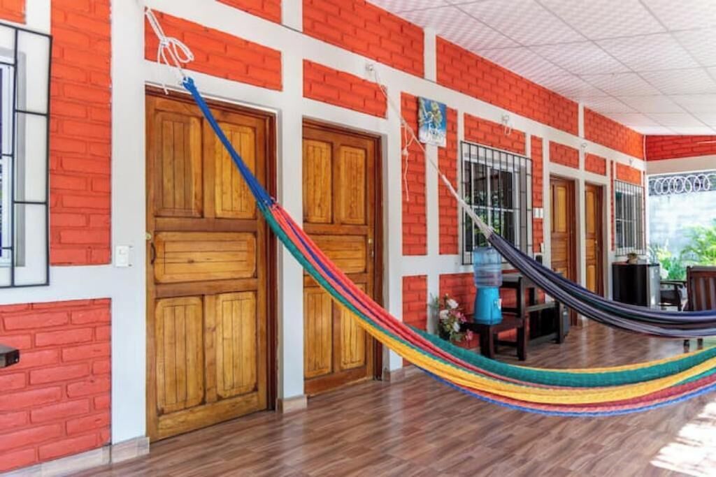 Una habitación con puerta de madera, una hamaca y una ventana.