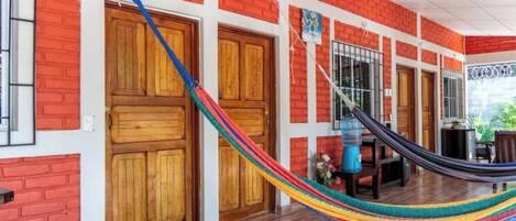 Una habitación con puerta de madera, una hamaca y una ventana.
