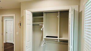A walk-in closet with open doors, revealing shelves and hanging space.