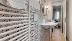 Un baño con baldosas estampadas, un lavabo blanco y un perchero para toallas.