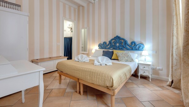 Un dormitorio con cama, mesitas de noche, lámpara y candelabro.