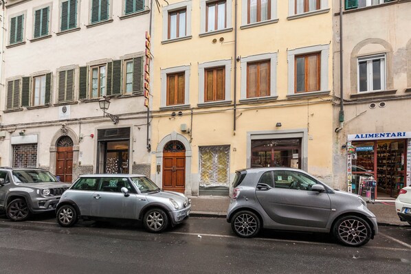 A street with parked cars and a building with a sign that reads "MENTARI". - Mamo Florence - Agnolo Apartment (Florence)
