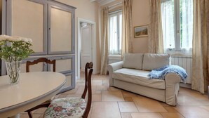 Una habitación con una mesa de comedor, sillas, un sofá y una ventana con cortinas.