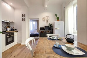 Une cuisine moderne avec des meubles blancs, une table à manger en bois et un réfrigérateur.