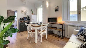 A compact living space with a dining area, kitchenette, and seating area. - Mamo Florence - Aida Apartment (Florence)